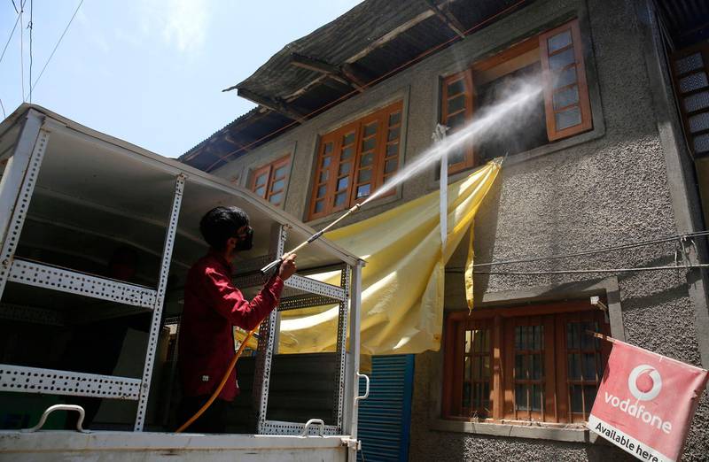 A government municipal worker sprays disinfectant in area during a funeral in Srinagar. EPA