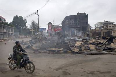 A man rides a motorcycle near a burned building that housed an orphanage for Muslim children in Lashio.