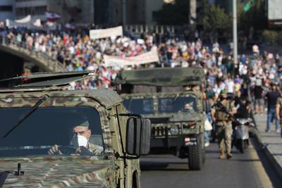Lebanese army vehicles escort crowds walking over a bridge linking the city on the first anniversary of anti-government protests.  Getty Images