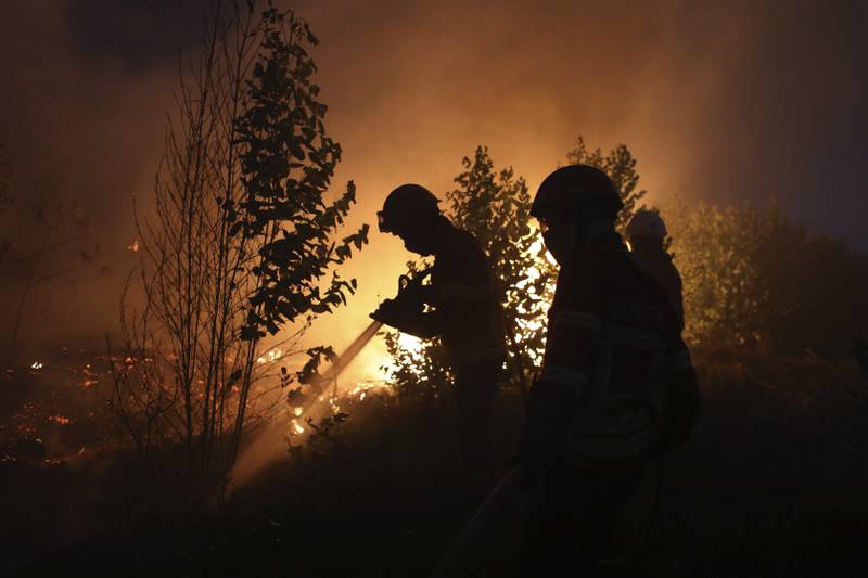 Firefighters work to put out a forest fire in the Rio Maior, Portugal, that has been burning for 12 days. AP