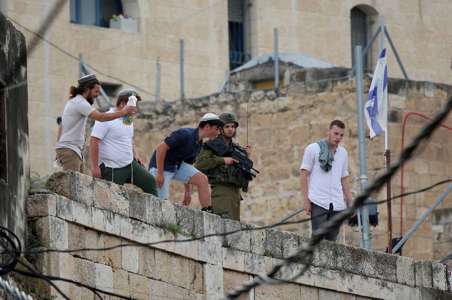 Jewish Israeli settlers watch Palestinian demonstrators in the Kasbah area of the Old City of Hebron in the West Bank, in April 2022. EPA