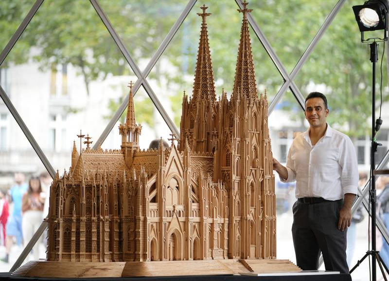 Woodcarver and artist Fadel Alkhudr from Syria poses beside his wooden model of Cologne Cathedral in the German city. He fled the civil war in his home country in 2015. AP