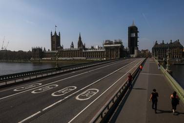 Pedestrians cross a quiet Westminster Bridge in view of the Houses of Parliament in London on April 9. Movement restrictions to prevent the spread of the coronavirus have been in place in the UK since March 23. Bloomberg