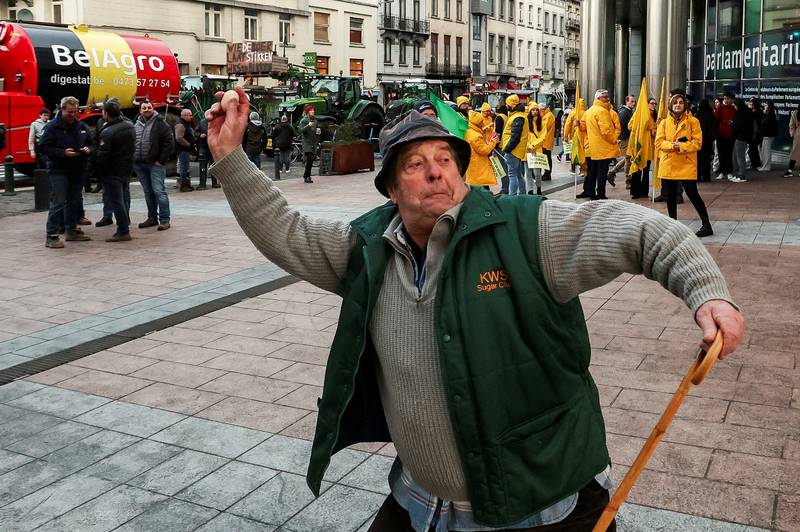 A farmer throws an egg towards police officers, as farmers from Belgium and other European countries use their tractors to blockade the European Parliament buildings, during a protest over price pressures, taxes and green regulations. Reuters