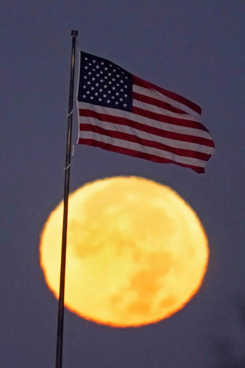 The full blue moon sets beyond an American flag in Kansas City, Missouri. AP Photo