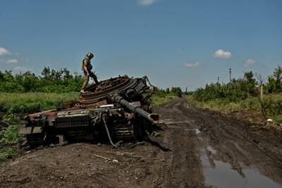 A Ukrainian soldier inspects a destroyed Russian tank in the village of Novodarivka, Luhansk region, in July. Reuters