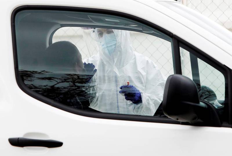 A health worker takes a swab sample at a drive-through covid testing site at La Fe Hospital in Valencia, Spain. EPA