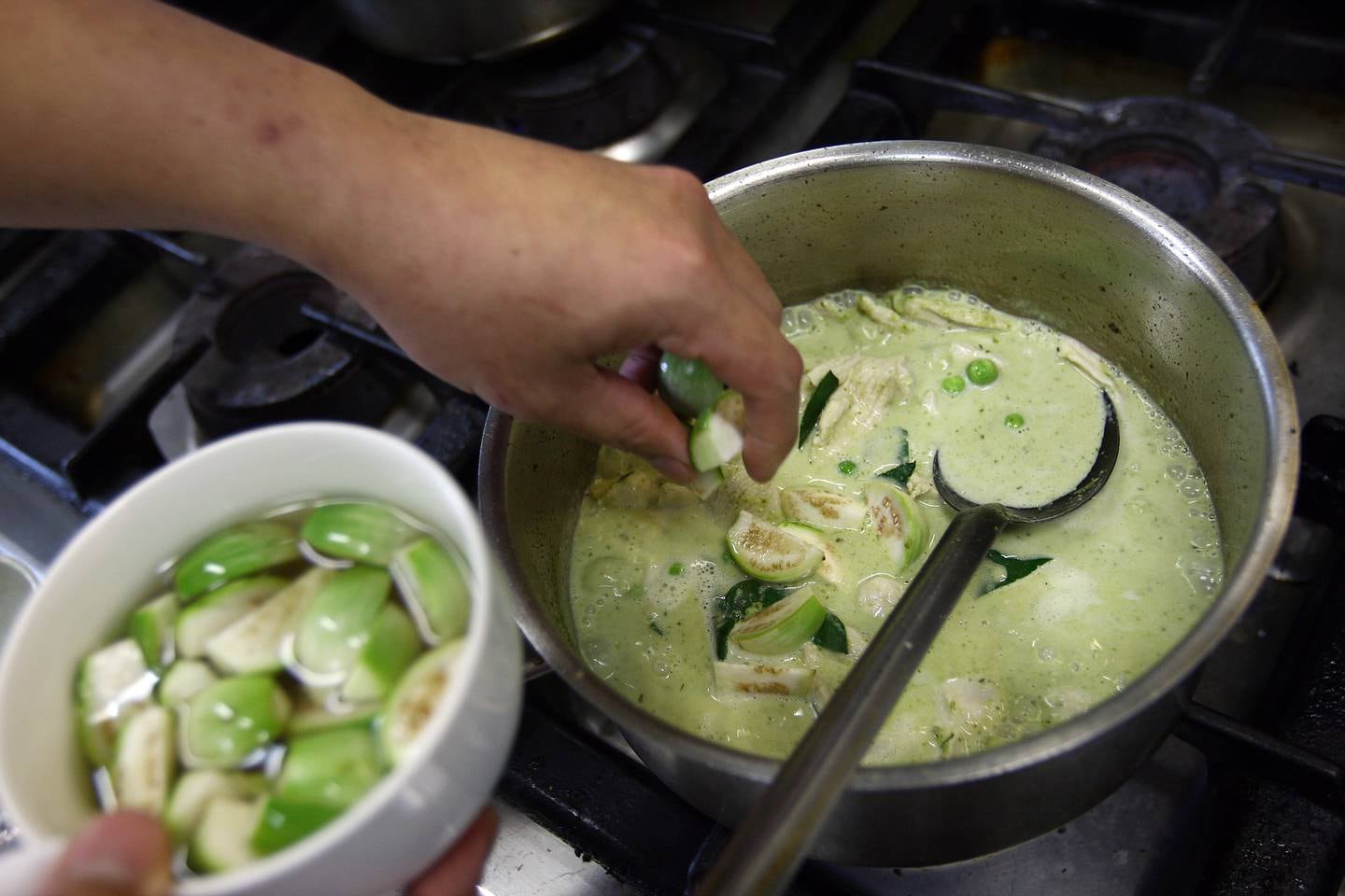 Dubai, United Arab Emirates- July 13,  2011:   Chef Paul Kennedy  adds Green Brinjals  to prepare Green Thai Curry at the Mango Tree restaurant  in  Dubai.  ( Satish Kumar / The National ) For Arts & Life