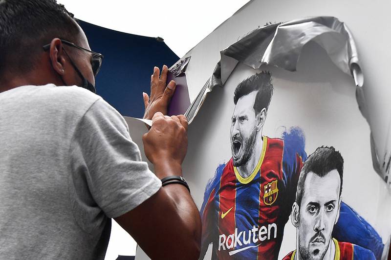 A worker removes posters featuring Argentinian forward Lionel Messi at Camp Nou.