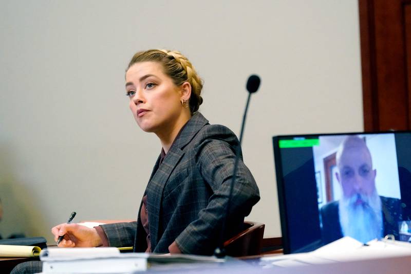 US actress Amber Heard listens as Travis McGivern, security for Johnny Depp, is seen on a monitor as he testifies remotely. AFP