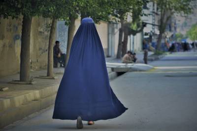 A burqa-clad woman walks along a street in Kabul on May 7, 2022. The Taliban had just imposed some of the harshest restrictions on Afghanistan's women since they seized power, ordering them to cover fully in public, ideally with the traditional burqa. AFP
