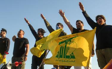 Supporters of the Lebanese Shiite movement Hezbollah perform a salute as they stand behind motorcycles carrying the group's flags in the southern Lebanese district of Marjayoun on the border with Israel on May 25, 2020. Twenty years after the withdrawal of Israeli forces from Lebanon, Hezbollah still enjoys wide support among youth regaled with tales of the Shiite group ending 22 years of Israeli occupation. / AFP / Mahmoud ZAYYAT
