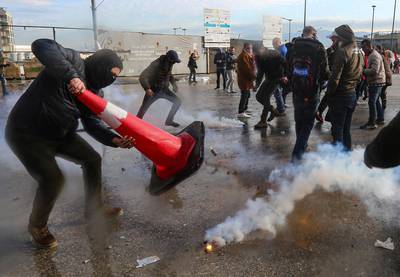 A protestor tries to extinguish a tear gas during a protest seeking to prevent MPs and government officials from reaching the parliament for a vote of confidence, in Beirut, Lebanon. REUTERS