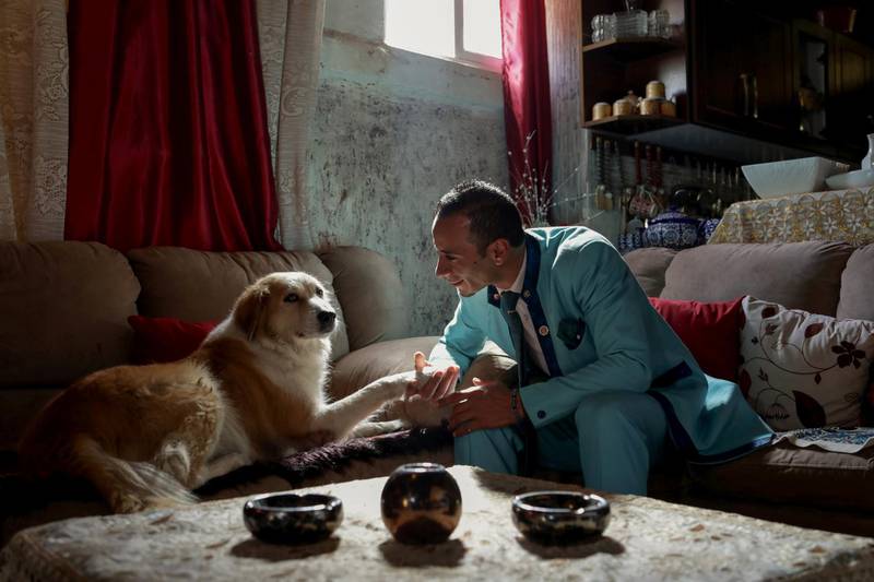Ali Sarsour plays with his dog at his home in Amman while wearing a suit he made. Reuters
