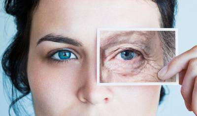 Young woman with photo of aged eye over her own. Getty Images