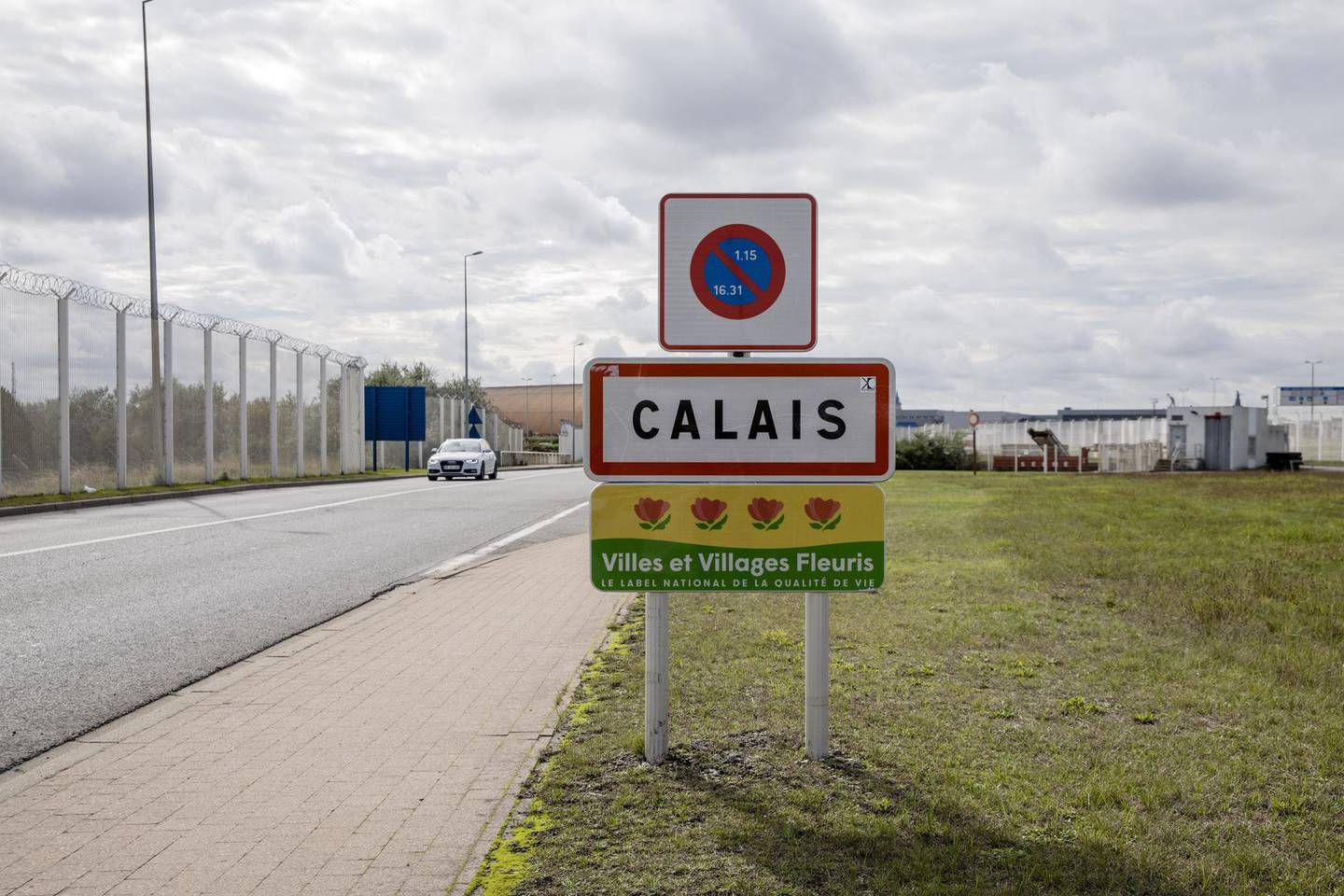 A sign for the city of Calais stands near a barbwire security fence on a road leading to the Port of Calais cross channel ferry terminal in Calais, France, on Monday, Oct. 7, 2019. The port of Calais on France’s northern coast has spent 6 million euros ($6.6 million) on facilities for customs officers, updated signage around freshly painted roads and huge extra parking lots for trucks. Photographer: Marlene Awaad/Bloomberg