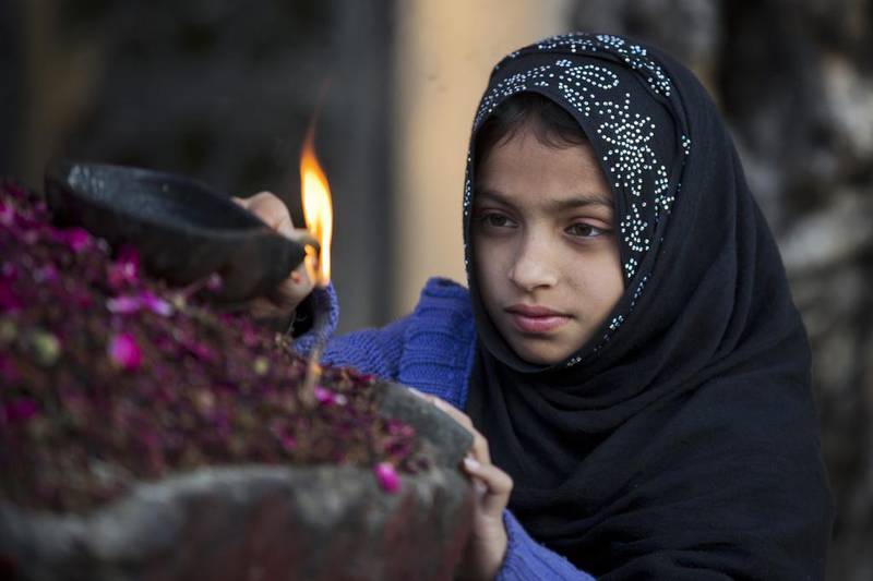 A Pakistani girl lights an oil lamp at a local shrine in suburbs of Islamabad, Pakistan.  B.K. Bangash / AP Photo