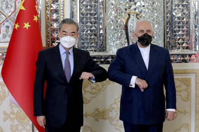 Iranian Foreign Minister Mohammad Javad Zarif, right, and his Chinese counterpart Wang Yi, pose for photos at the start of their meeting in Tehran, Iran, Saturday, March 27, 2021. Iran and China on Saturday signed a 25-year strategic cooperation agreement addressing economic issues amid crippling U.S. sanctions on Iran, state TV reported. (AP Photo/Ebrahim Noroozi)