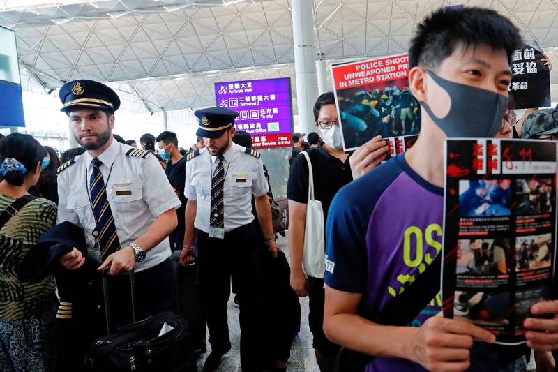 Pilots walk past anti-extradition bill protesters at a mass demonstration after a woman was shot in the eye during a protest at Hong Kong International Airport, in Hong Kong, China.  Reuters