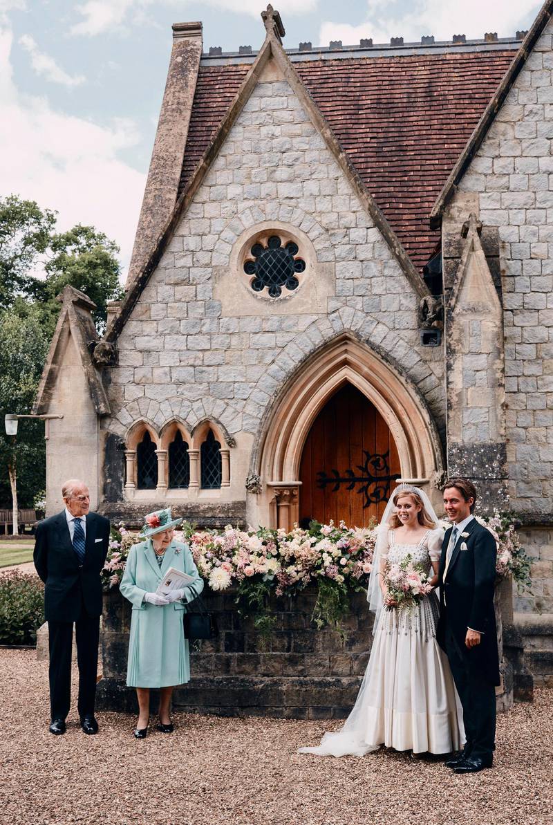 In this photograph released by the Royal Communications of Princess Beatrice and Edoardo Mapelli Mozzi, Britain's Queen Elizabeth II and Prince Philip stand alongside Princess Beatrice and Edoardo Mapelli Mozzi outside The Royal Chapel of All Saints at Royal Lodge, Windsor, England, after their wedding on Saturday July 18, 2020. Princess Beatrice wore a vintage dress loaned to her by Queen Elizabeth II at her wedding, Buckingham Palace said Saturday as it released official photographs from the small family event. (Benjamin Wheeler/Royal Communications of Princess Beatrice and Edoardo Mapelli Mozzi via AP)