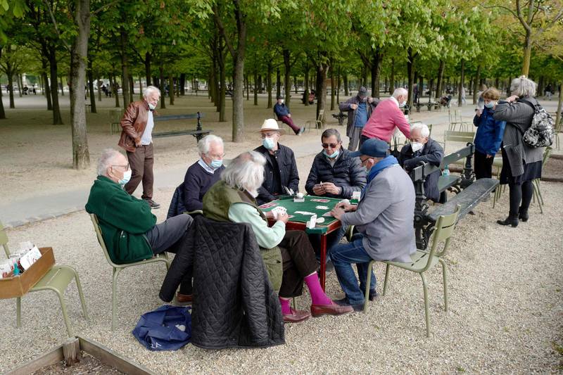 People wearing protective face masks play cards in the Luxembourg Garden in Paris, France. AFP