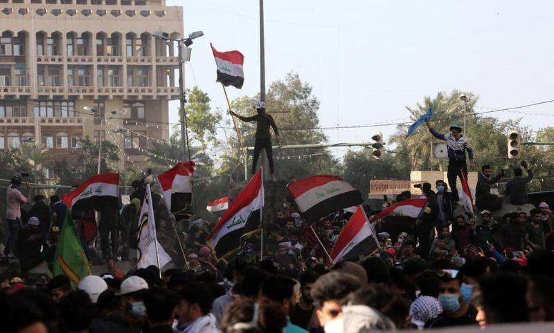Iraqi protesters carry the Iraqi national flag as they gather on concreat blocks which were used by security forces to close the Al-Khilani square in central Baghdad, Iraq.  EPA