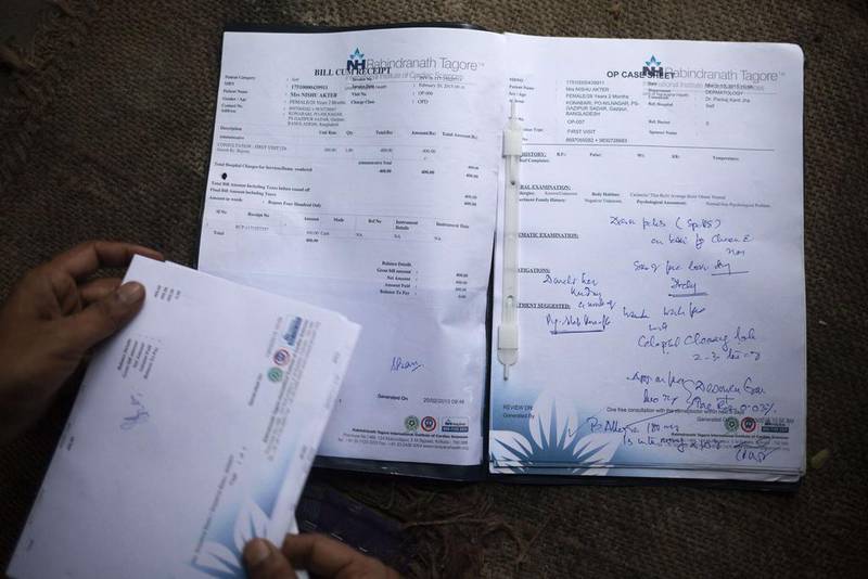 Rawshan Ara, shows her medical records — which are in another name — in the village of Kalai. Suvra Kanti Das / AFP