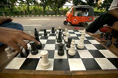 Motorcycle taxi drivers play chess in central Jakarta while waiting for passengers.