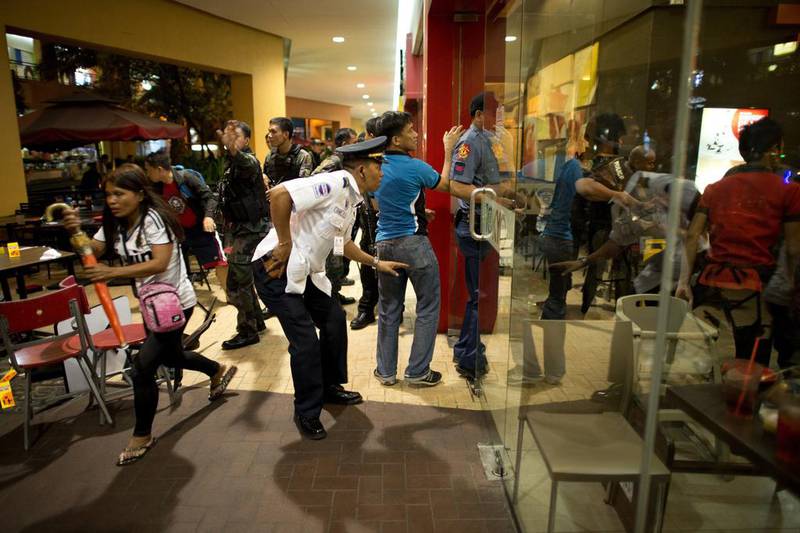 Diners rush from a restaurant as an officer from the Philippines police moves towards the scene of an attempted robbery on a jewellery store inside SM Mall of Asia in Manila on March 30, 2014. Noel Celis / AFP