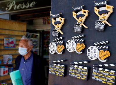 A man wearing a protective face mask stands near magnets featuring the Cannes Film Festival on the Croisette in Cannes as the French Riviera prepares for the 2021 edition of the Cannes Film Festival which will take place next July, in France, June 3, 2021.  REUTERS/Eric Gaillard