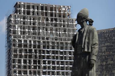 A statue representing the Lebanese expatriate is seen in front of a building that was damaged by the explosion. AP Photo