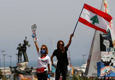 Anti-government protesters stand on the top of their cars and wave a Lebanese flag and a cardboard fist labelled "Revolution", as they protest by driving through the streets to express rejection of the political leadership they blame for the economic and financial crisis, in Beirut, Lebanon. AP Photo