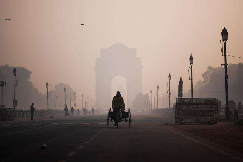 A man rides a rickshaw along a street near India Gate in heavy smoggy conditions in New Delhi on December 6, 2019. (Photo by Jewel SAMAD / AFP)