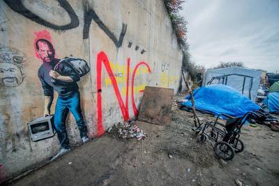epa05080943 A tag of the artist Banksy representative Steve Jobs in the camp called 'The Jungle' in the port of Calais, France, 25 December 2015.  By this Banksy tag means that Steve Jobs was also a Syrian migrant son come Holms. He said. "We are often led to believe that immigration will pump a country's resources, but Steve Jobs was the son of a Syrian immigrant Apple is the most profitable company in the world, it pays more than 7 billion per year in taxes - and it is only because they have left back a young man of Homs "  EPA/STEPHANIE LECOCQ