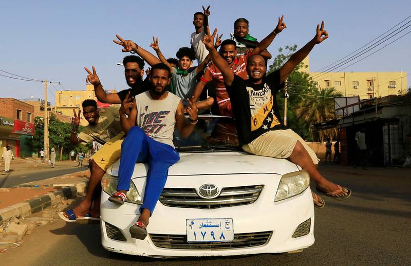 Sudanese people ride atop a car chanting slogans as they celebrate on Friday. Reuters