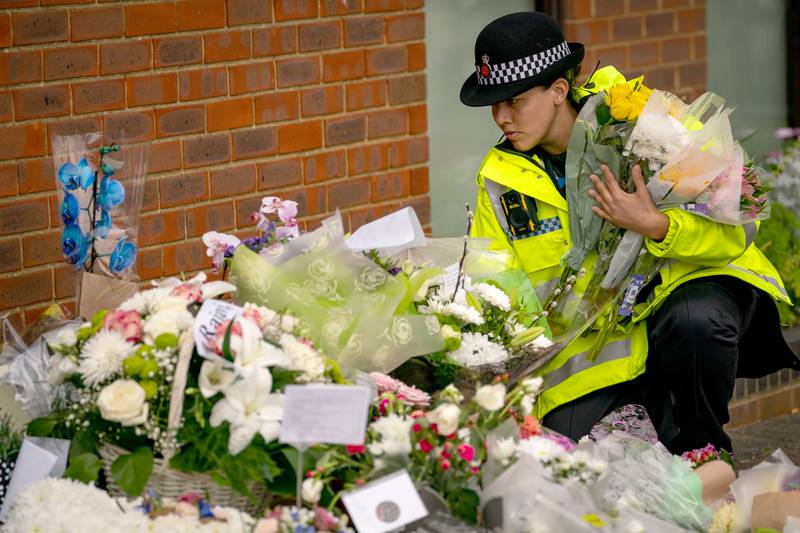 A police officer arranges flowers and tributes outside Belfairs Methodist Church in Leigh-on-Sea, where Conservative MP Sir David Amess died. PA