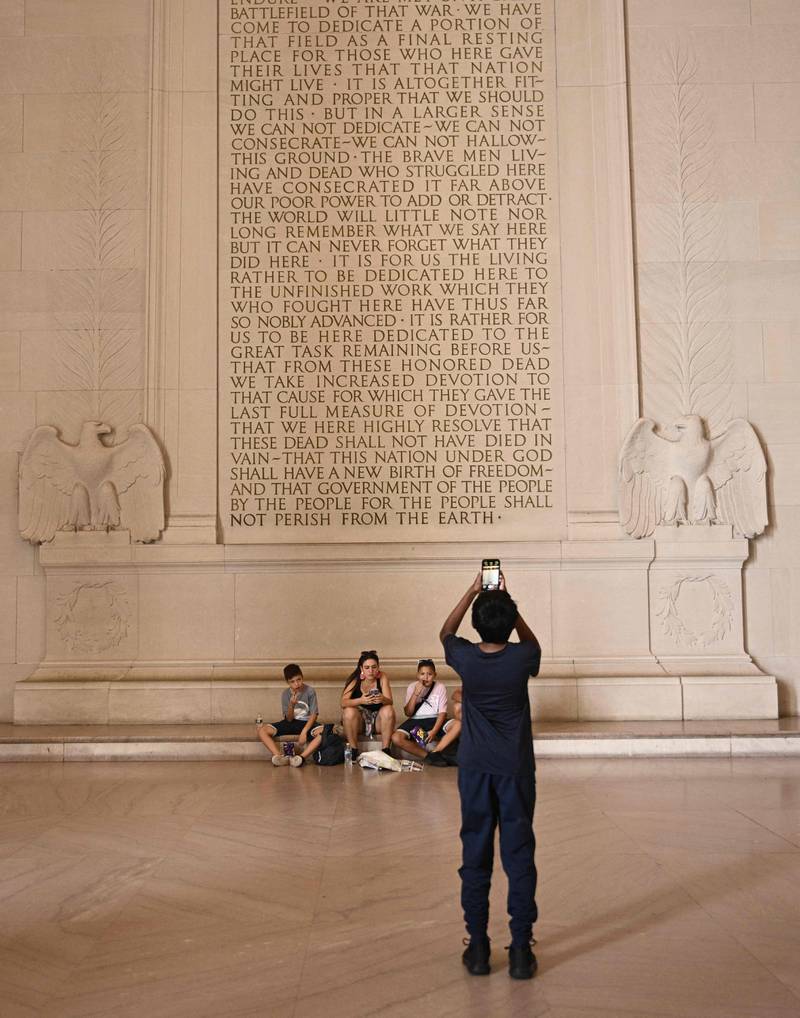 Tourist visiting the Lincoln Memorial sit under the engraving of the Gettysburg Address of in Washington, DC, on July 27.  AFP