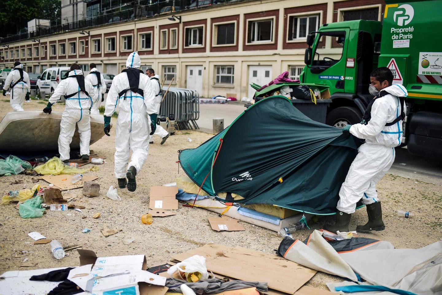 TOPSHOT - Workers clean up a migrants' makeshift camp along the Canal de Saint-Martin at Quai de Valmy in Paris, following its evacuation on June 4, 2018. More than 500 migrants and refugees were evacuated on early June 4, 2018 from a makeshift camp that had been set up for several weeks along the Canal. / AFP / Lucas Barioulet
