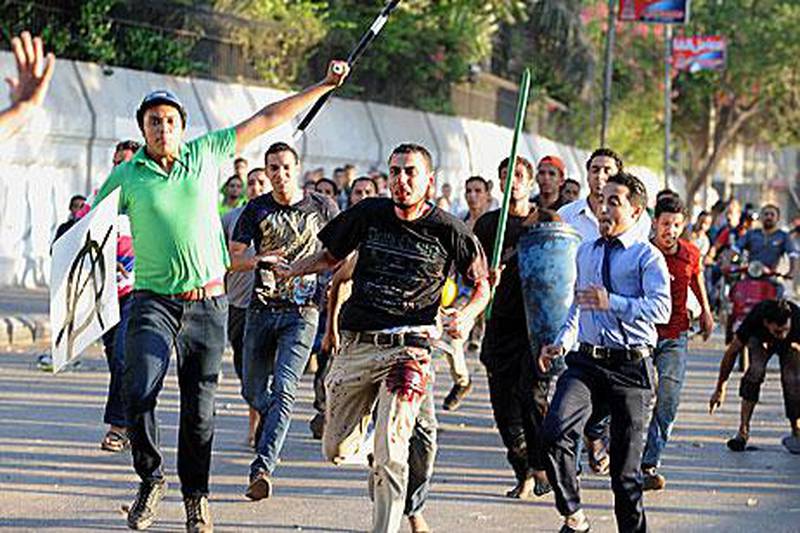 A supporter of deposed Egypt president Mohammed Morsi, centre, is chased by Pro-army supporters in deadly clashes in Cairo today.