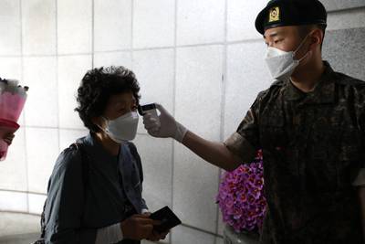 A South Korean woman receives body temperature check from soldier as she arrive visits at the Seoul National Cemetery during a 65th anniversary of the Memorial Day amid coronavirus pandemic in Seoul, South Korea. South Korea marks the 65th anniversary of the Memorial Day for people who died during the military service in the 1950-53 Korean War. Getty
