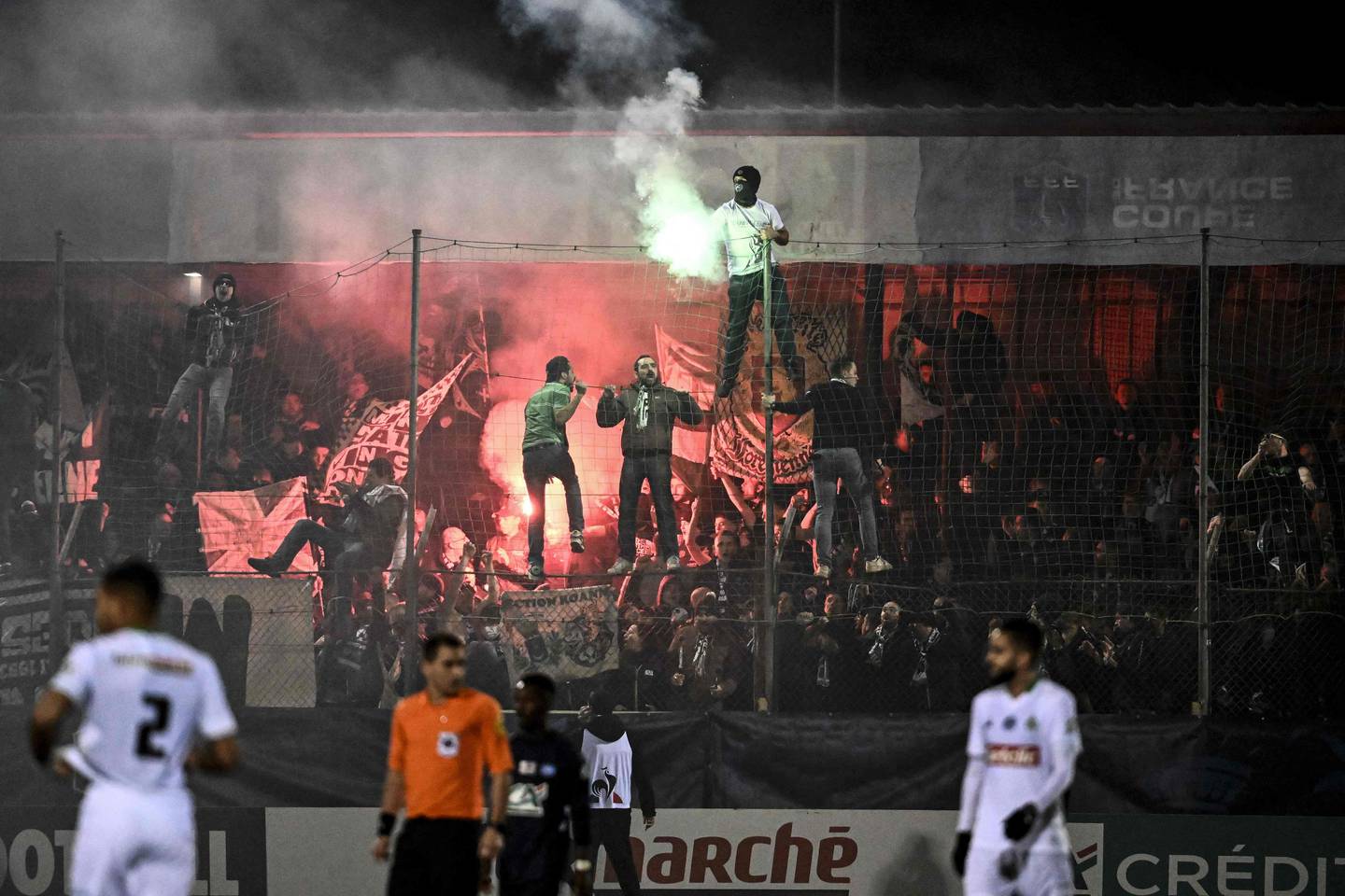 People in the crowd light flares during the French Cup match between Jura Sud and Saint-Etienne. The match was interrupted shortly after for around 20 minutes. AFP