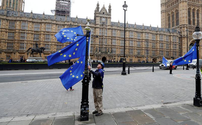 FILE PHOTO: An anti Brexit protester adjusts his EU flags outside the Houses of Parliament in London, Britain October 19, 2017.  REUTERS/Peter Nicholls/File Photo