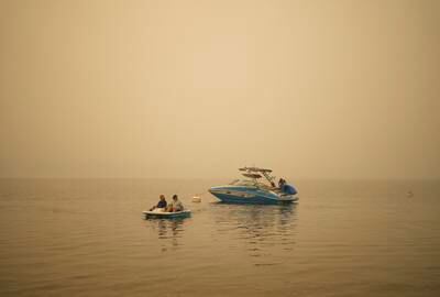 Pat Manzuik and her husband Trevor use a paddleboat to get back to their home they were evacuated from due to the Lower East Adams Lake wildfire, in Scotch Creek, Canada. AP