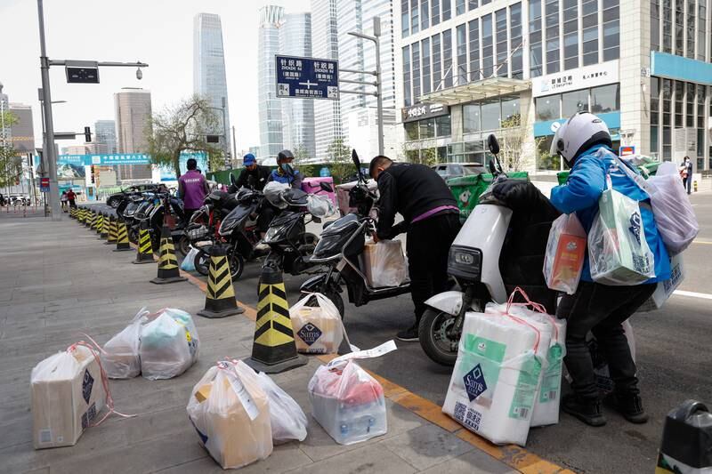Delivery riders load packages for distribution in Beijing. EPA