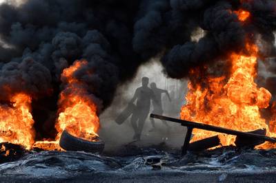 A protester throws a tyre on to a fire to block a road during a protest in north of Beirut, Lebanon in October 2019. EPA