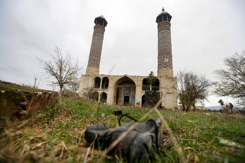 A military boot lies on the grass in front of the Aghdam Mosque in Agdam, prior to the Azerbaijani forces being handed control in the separatist region of Nagorno-Karabakh, Thursday, Nov. 19, 2020. The mosque itself is an especial sore point. In the years after the local population was driven out the mosque was turned into a stable for cattle and swine. Although ethnic Armenian forces tried to keep outsiders away from Aghdam, some camera-bearing visitors slipped in and their photos of the mosque's defilement outraged Azerbaijanis. (AP Photo/Sergei Grits)