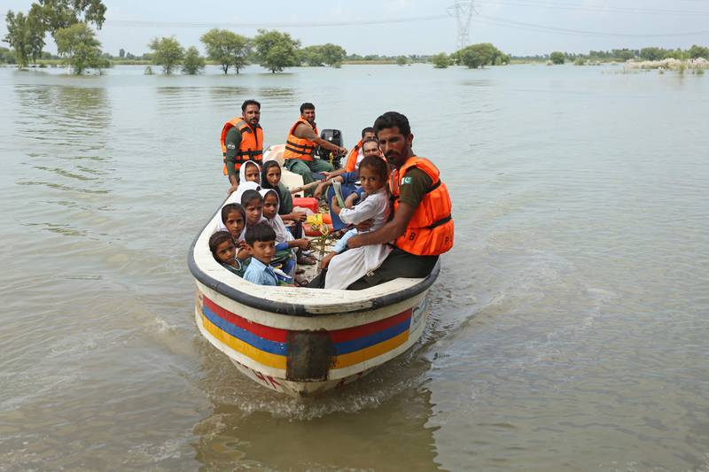 Rescue workers use a boat to drop children back home after school in Dera Ghazi Khan district. AFP