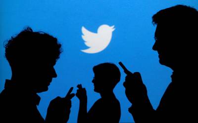 FILE PHOTO: People holding mobile phones are silhouetted against a backdrop projected with the Twitter logo in this illustration picture taken September 27, 2013. REUTERS/Kacper Pempel/Illustration/File Photo/File Photo
