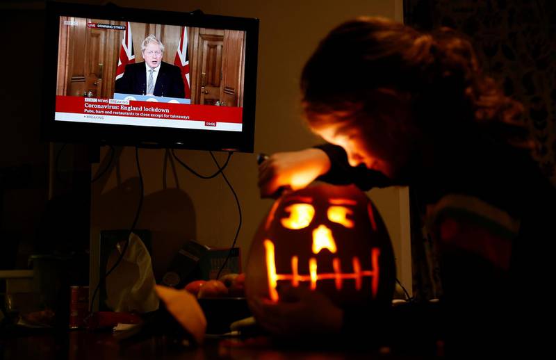 8 year old Alice Wilkinson carves a halloween pumpkin at her home in Manchester as Boris Johnson speaks at a news conference. Reuters