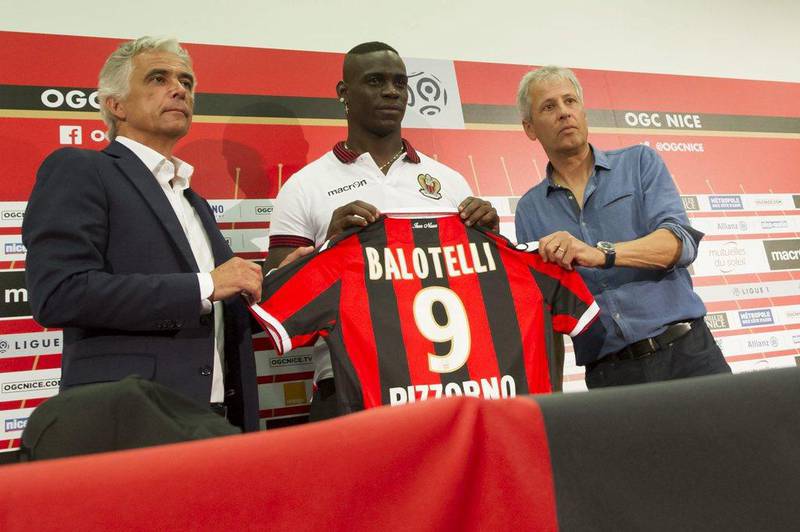 OGC Nice forward Mario Balotelli attends a press conference and presents his shirt with team president Jean-Pierre Rivere, left, and manager Lucien Favre, right. Olivier Anrigo / EPA